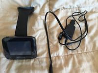 Front view of GPS unit attached to suction mount arm alongside charger cable