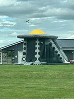 Full view of grey and black UFO inflatable with yellow dome and slide attachment