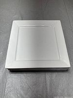 Top view of stacked white square ceramic serving platters showing flat serving surface and clean white color.
