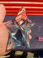 Front view of the star-shaped Angel Mugler perfume bottle held in hand showing unique design and materials.