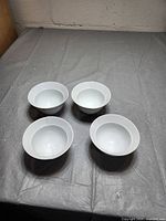 Four white ceramic bowls placed on a gray surface, showing their shape and quantity.
