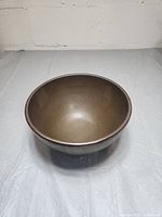 Top and side view of a heavy decorative bowl with a brown smooth finish.