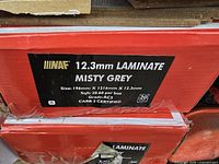 Box label showing 12.3mm laminate flooring in Misty Grey, plank size 196mm x 1216mm, coverage 20.60 sq ft per box, CARB 1 certified.
