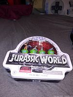 Jurassic World themed PEZ dispenser set in original packaging, showing three dinosaur heads on green bases
