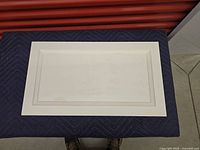 Four white shaker style cabinet doors laid on a dark padded surface, showing front faces with visible recessed panel detailing.