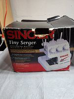 Box of Singer Tiny Serger overeding machine showing product image and model 14SH654.