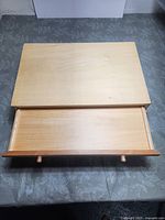 Top view of the wooden drawer unit showing open shallow flat drawer interior and smooth wood surface.