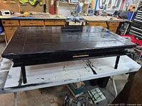 Top view of black coffee table closed, showing smooth painted surface and a handle on the front.