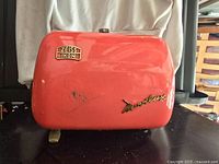 Front view of the red Zeiss Ikon Novolux casing showing gold logo and model name with visible surface scratches.