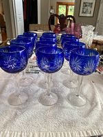 12 cobalt blue stem glasses arranged in rows showing detailed cut patterns on the bowls.