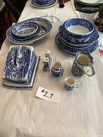 Full spread of 16-piece blue and white china set on white paper, including plates, bowls, covered cheese dish, salt and pepper shakers, creamers, and pitchers.