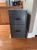 Front view of gray metal 2-drawer filing cabinet with black handles and lock on top drawer