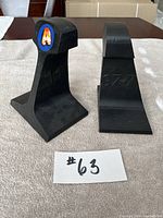 Front and one side view of two black steel rail bookends, one with a colorful 'A' sticker, the other plain with '1977' stamped.