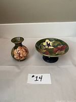 Two-piece set of vintage Moorcroft vase and dish with hibiscus flower decoration on a green background, front view.
