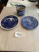 Top down view of three blue and white china pieces – two plates and one cylindrical planter, numbered #31.