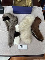 Four vintage fox fur pelt pieces displayed on fabric with blue box in background.