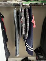 Side view of clothes hanging on a rack, includes various golf bottoms and dresses showing color and pattern variety.