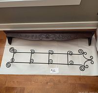 Both wooden shelf and iron wall hanging displayed on floor showing full length and design