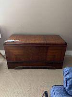 Front view of large cedar chest showing polished wood finish and decorative base trim.