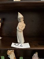 Porcelain figurine of a girl holding a rooster, standing on a dark shelf, photo taken to show the main lot item.