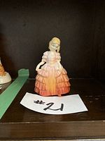 Porcelain figurine of a young girl in a ruffled dress with gradient colors, identified as Royal Doulton 'Rose' H.N. 1368