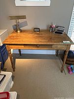 Front view of rustic wood office desk with drawer, showing turned legs and finished wood surface.
