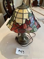 Stained glass Tiffany-style table lamp front view showing floral motif and metal base.