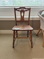 Front view of vintage wooden chair showing the carved backrest, solid wood seat, and turned legs.