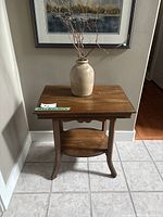 Full view of the vintage wooden entry table with a ceramic vase on top.