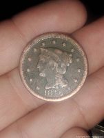 Photo of a 1846 US Large Cent coin held in fingers showing the Liberty Head design, patina visible