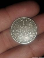 Obverse of the 1919 French 1 franc coin showing denomination, date, and motto with olive branch decoration.