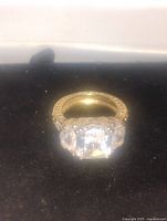 Front view of gold-toned ring with large cubic zirconia stone and small stones on the band.