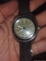 Front view of the watch face being held in hand showing the dial and luminous markers.