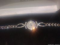 Front view of silver tone ladies wristwatch with rhinestone encrusted bezel and linked chain bracelet strap.