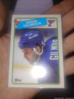 Front view of the 1984 Doug Gilmour hockey card in St. Louis Blues uniform, held in hand, showing the card's design, colors, and Topps logo.