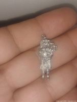 Close-up of sterling silver Scottish bagpiper charm held in hand, showing detailed design and loop for attachment.