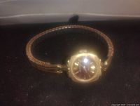 Front angle of the women's gold tone Whitnaur wristwatch showing the watch face and expandable metal band.