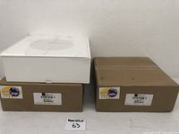 Two cardboard boxes containing the speakers, one brown and one white box visible.