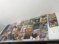 Wide view of 19 assorted comic books laid out on a table featuring various characters and titles.