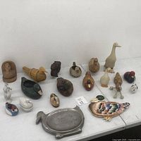 Full view of all 18 assorted duck figurines on display table showing various materials and sizes