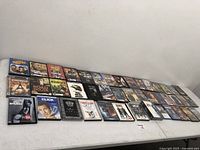 Wide view of 26 assorted DVDs laid out in rows on a white surface, includes movies and TV series DVDs.