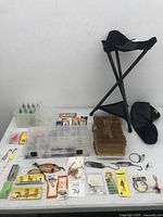 Full overview of all fishing accessories including boxes, packs, stool, and loose items on table.