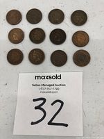 Twelve U.S. Indian Head pennies arranged in rows on a flat surface showing obverse (heads) side with an auction lot number in the image.