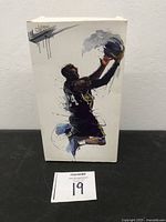 Front view of the box featuring artistic illustration of Kobe Bryant dunking a basketball, branding includes Nike and Legend Creation.