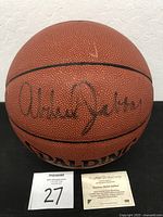 Front view of signed basketball with certificate card below