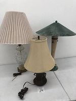 Three lampshades each on its lamp base arranged together showing different styles and materials.