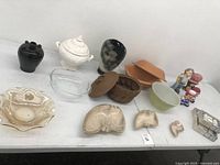 Overview of mixed dishes, bowls, small containers and figurines on white surface