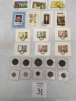 View of assorted international postage stamps with various themes including Apollo 11 and Olympic Games, along with coins in protective holders, some dated 1930.