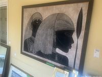 Large framed cloth art of two Egyptian style figures on wall with spear and detailed bead jewelry, hair, and headdress patterns.