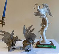 Two metal fighting rooster statues in brassy finish displayed with large Lladro cockatoo figurine on wooden base signed by Giuseppe Armani.
